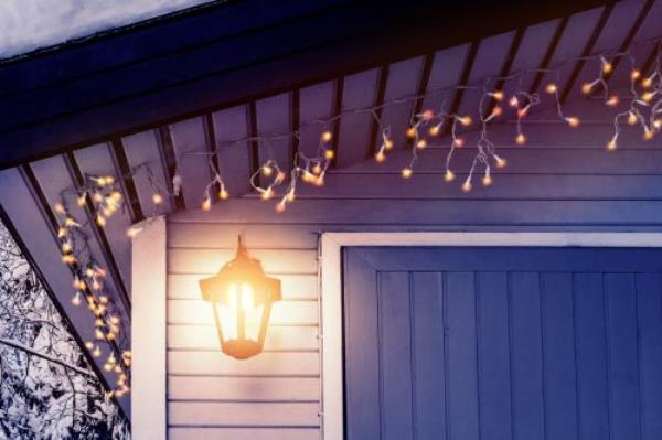 Porch of the house is decorated in the traditio<em></em>nal Scandinavian style with a lantern and Christmas lights - co<em></em>ncept of home warmth, comfort, family holiday.