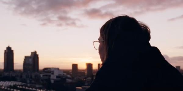 Person looking out at a city in Occupied City trailer