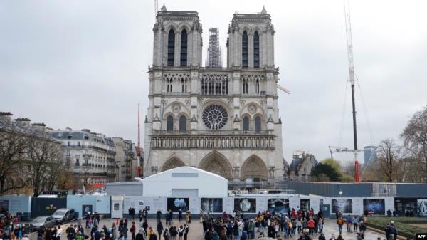 People stand in front of Notre-Dame de Paris Cathedral during the reco<em></em>nstruction work on the Ile de la Cite in Paris, on Dec. 8, 2023, one year to the day before the cathedral, which was ravaged by fire in 2019, is due to reopen. 