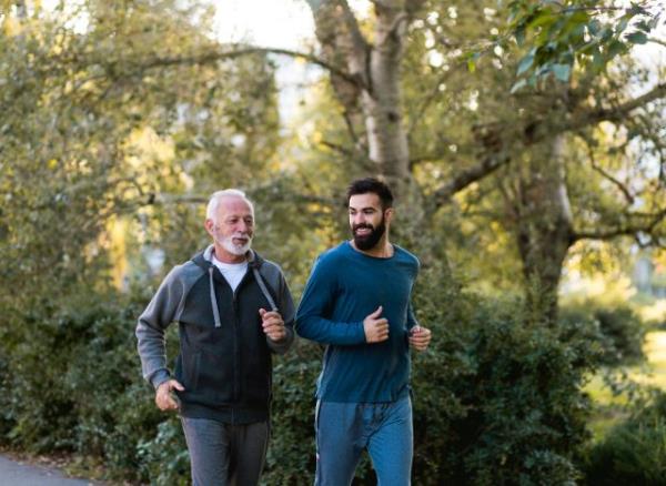 father and son jogging outdoors on trail with foliage