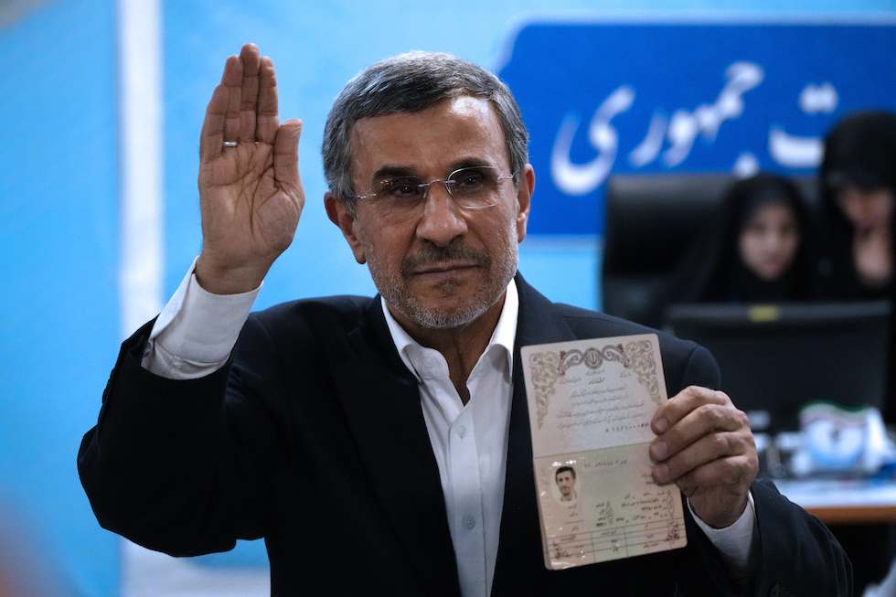 Former Iranian President Mahmoud Ahmadinejad shows his passport to photographers as he announces his candidacy 