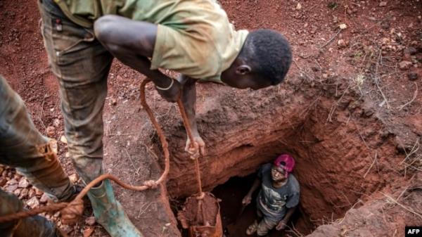 FILE - Tanzanian miners extract soil to look for gold at an open-pit gold mine in Nyarugusu, Geita Region, May 27, 2022.