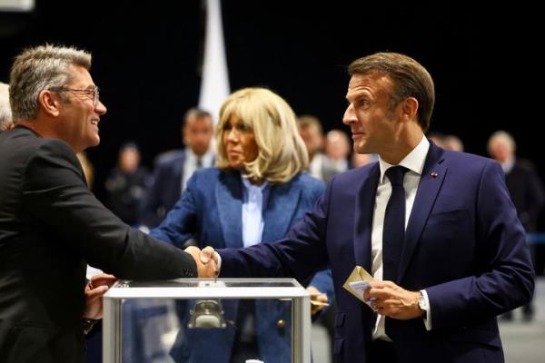 French President Emmanuel Macron, right, shakes hands with a polling station official during the European election, Sunday, June 9, 2024 in Le Touquet-Paris-Plage, northern France. Polling stations opened across Europe on Sunday as voters from 20 countries cast ballots in elections that are expected to shift the European Unio<em></em>n's parliament to the right and could reshape the future direction of the world's biggest trading bloc. (Hannah McKay/Pool via AP)