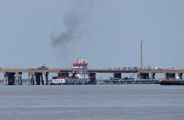 A tugboat works to maneuver a barge away from the Pelican Island Bridge in Galveston, Texas.