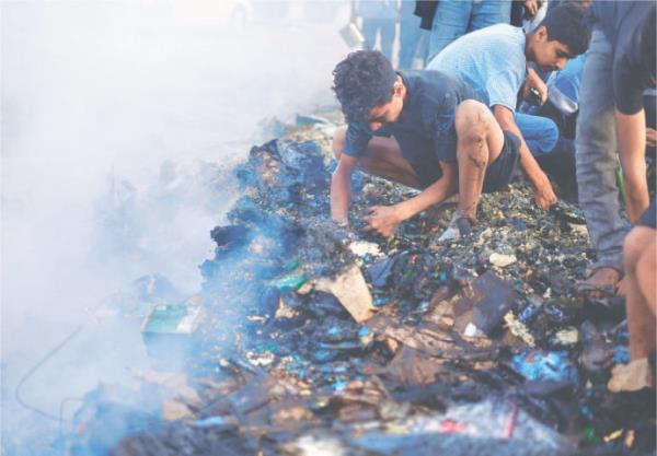 Palestinians search for food among burnt debris in the aftermath of an Israeli strike in Rafah, on Monday.—Reuters