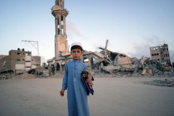A Palestinian boy carrying his prayer mat poses before joining the morning Eid al-Adha prayer in southern Gaza's Khan Younis, on the first day of the Muslim holiday marking the end of the Hajj pilgrimage to Mecca, on June 16, 2024.