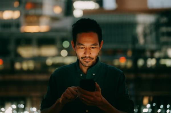 Man using smartphone in city at night