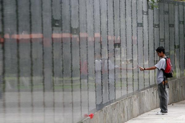 A boy touches a large stone wall with thousands of names etched on it.