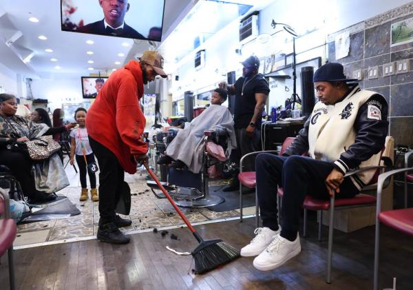 Nathan McCarthy, 49, sweeps up inside E’Studios barber shop and salon, directly across from the Austin District police station, on Oct. 25, 2023. McCarthy, currently homeless, lives in a tent in one of the police station’s parking lots.