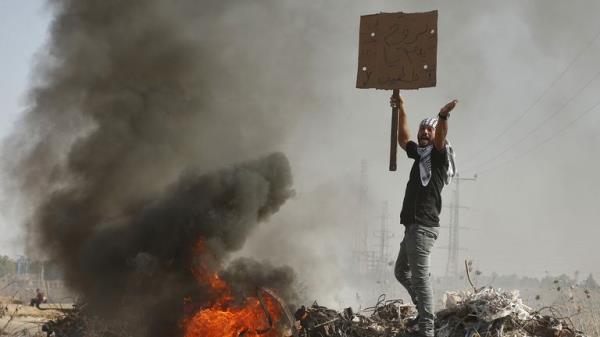 A Palestinian protester holding a sign shouts during clashes with Israeli troops near the border with Israel, in the east of Gaza City October 16, 2015. The unrest that has engulfed Jerusalem and the occupied West Bank, the most serious in years, has claimed the lives of 34 Palestinians and seven Israelis. The tension has been triggered in part by Palestinians' anger over what they see as increased Jewish encroachment on Jerusalem's al-Aqsa mosque compound, which is also revered by Jews as the l
