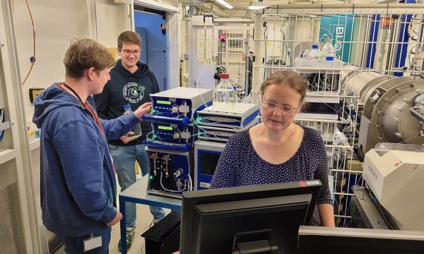 Three scientists are working in a room full of experimental equipment for X-ray experiments.