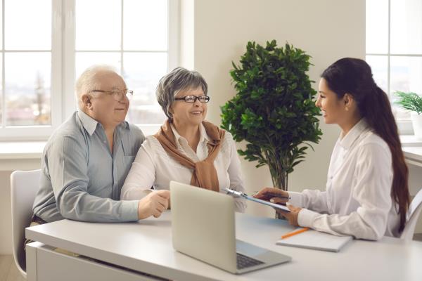 Two retirees talk to a tax co<em></em>nsultant in a well lit room.