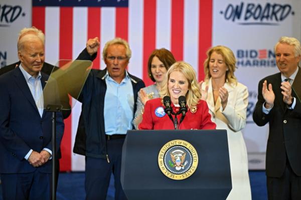 Kerry Kennedy speaking at a campaign rally for President Joe Biden in Philadelphia, with Joe Kennedy II, Kathleen Kennedy Townsend, Rory Kennedy, and Christopher Kennedy standing behind her.
