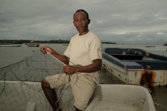 A man with a fishing net on a creek.