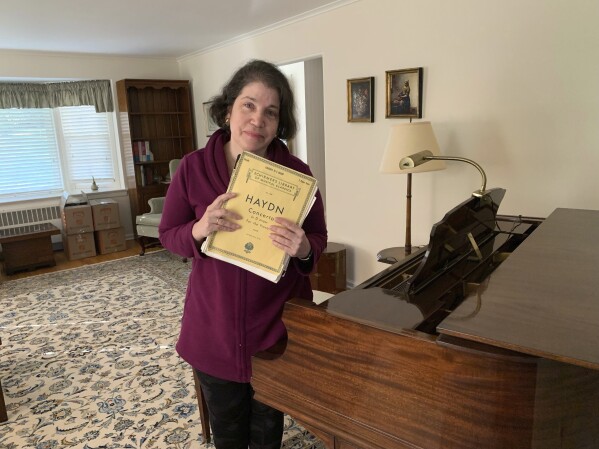 Anne D'Innocenzio stands by her family piano at her childhood home in suburban New Jersey, on April 3, 2023, hours before movers came to take it away to its new owner. (Courtesy Anne D'Innocenzio via AP)