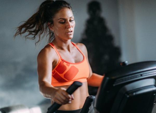 fit woman on the elliptical, co<em></em>ncept of treadmill or elliptical which is more effective