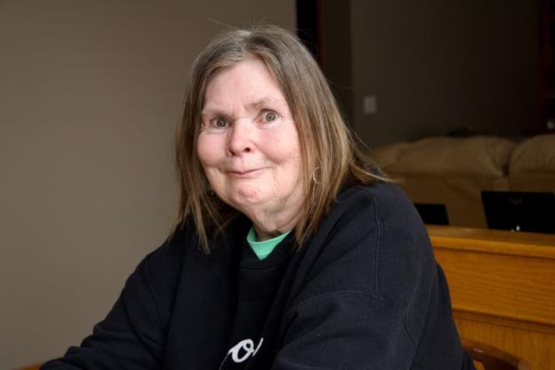 An older woman with shoulder-length, dark blo<em></em>nde hair and hazel eyes smiles at the camera.