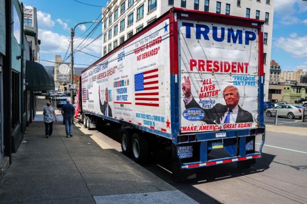 Pedestrians walk past a trailer-truck promoting former US President Do<em></em>nald Trump parked on a street in Scranton, Pennsylvania on April 15, 2024.