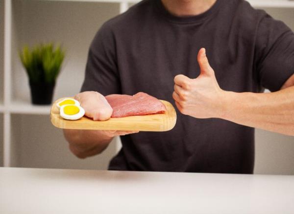 man holding plate of protein, co<em></em>ncept of tips for men to lose belly fat