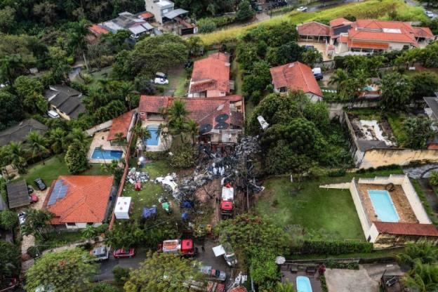 An aerial view of houses, with wreckage from a plane that crashed behind one of the houses.
