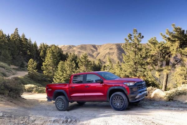 Side view of Colorado Trail Boss in scenic area with mountains, trees and a dirt road.
