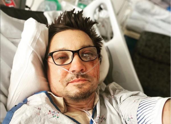 Jeremy Renner smiling from a hospital bed. 