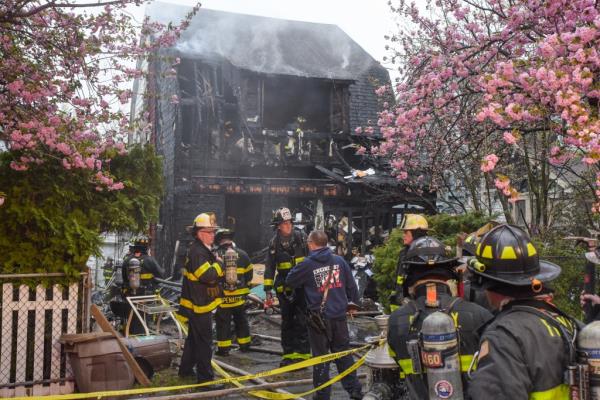 Firefighters gather outside the home, which is still steaming. 