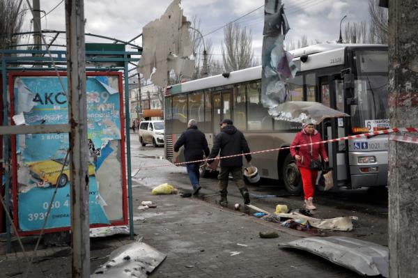 Local residents walk at the scene after a deadly Russian shelling that hit a bus station in Kherson.