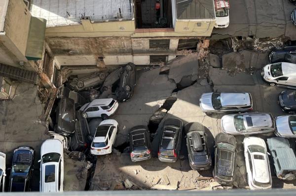 Cars fall into the collapsed top floor of a parking garage. 