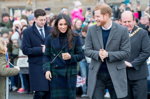 Photo fo Harry and Meghan walking with fans behind them
