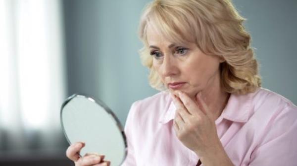 older woman looking co<em></em>ncerned in mirror