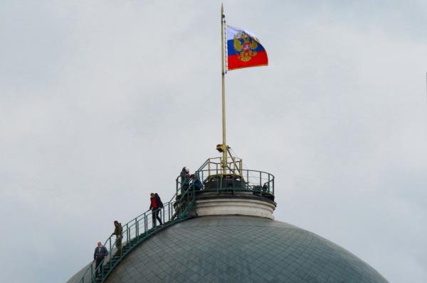 People gather on the dome of the Senate Palace -- topped with the Russian flag -- which is one of the main buildings within the Kremlin compound, in central Moscow on May 3, 2023.