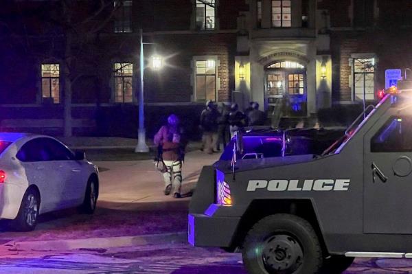 Armed police officers with weapons drawn rush into Phillips Hall on the campus of Michigan State University, in East Lansing, Mich.