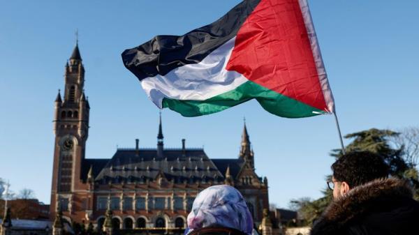 Protesters hold a Palestinian flag as they gather outside the Internatio<em></em>nal Court of Justice (ICJ) , in The Hague. Pic: Piroschka van de Wouw/Reuters