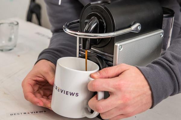 Person holding cup under spout on Nespresso machine