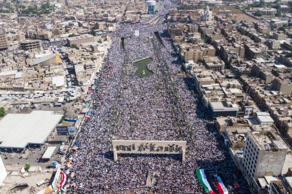 An overhead shot of a massive crowd of demo<em></em>nstrators in Baghdad surrounded by buildings on all sides.